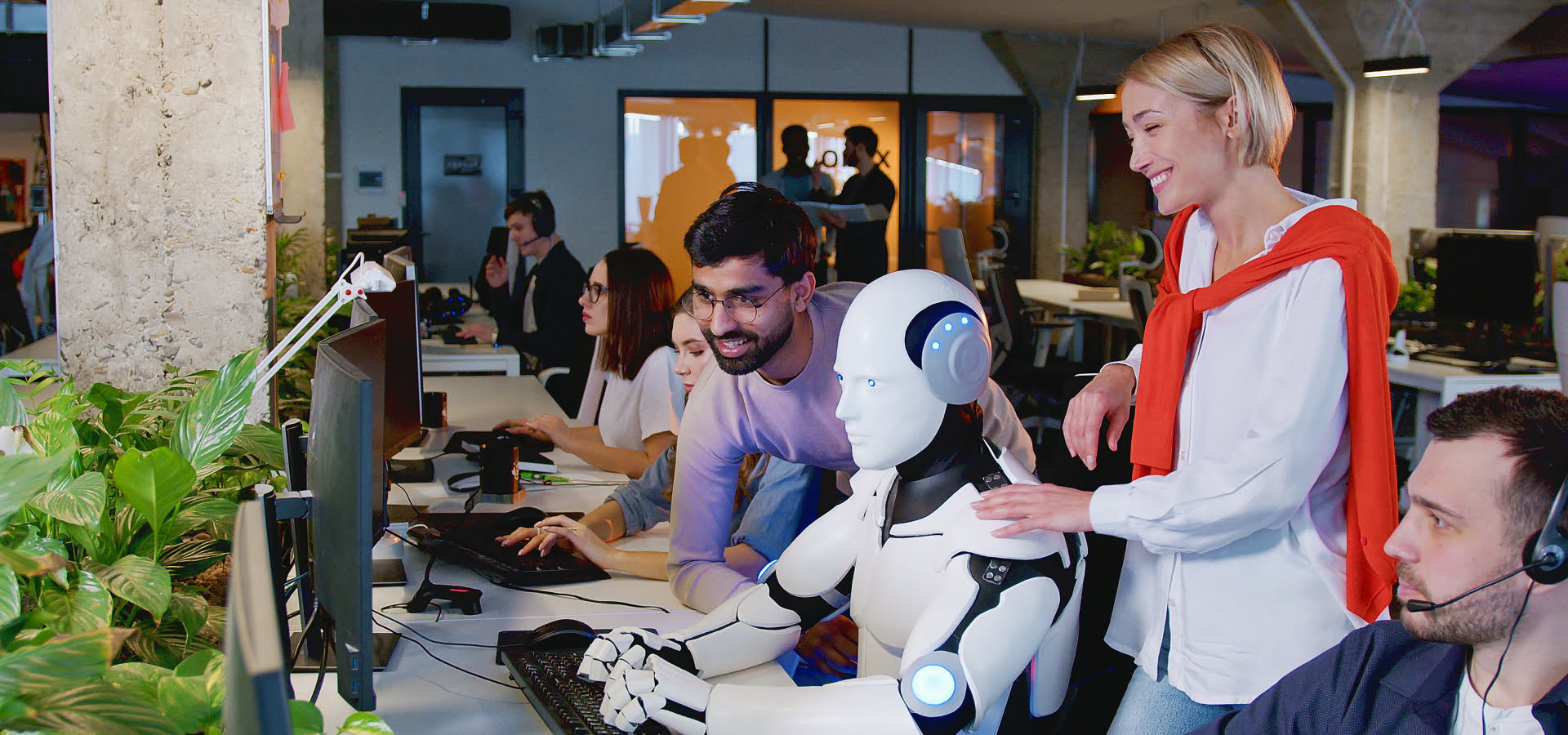 Humanoidalny robot współpracuje razem z pracownikami przy laptopie